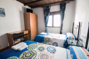 1 dormitorio con 2 camas, escritorio y ventana en El Tirol, en Cantagallo