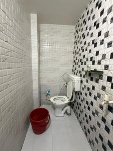 a bathroom with a toilet and a red bucket at Shri Raghuveer guest house in Ayodhya +9 photos