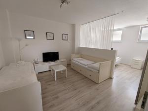 a white living room with a couch and a tv at Antonio Appartement in Steinabrückl