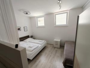 a small white bedroom with a bed and a window at Antonio Appartement in Steinabrückl
