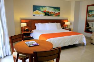 a hotel room with a bed and a table with a table at Hotel Atrium Plaza in Barranquilla