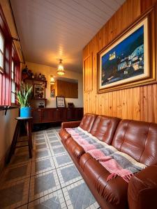 a living room with a brown leather couch at Nuh Hostel in Ouro Preto