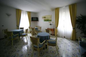 una sala da pranzo con tavoli, sedie e finestre di Hotel Riviera a Deiva Marina