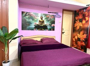 a bedroom with a purple bed with a painting on the wall at SM Guest Room in Mangalore