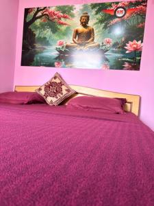 a bedroom with a purple bed with a painting on the wall at SM Guest Room in Mangalore