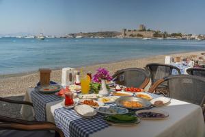 a table with food on the beach with the water at Artemis Hotel in Bodrum City