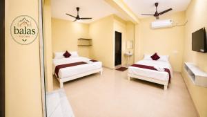 a hotel room with two beds and a tv at Bala's Rooms in Tirunelveli