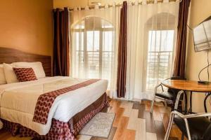 a bedroom with a bed and a table and a desk at Hôtel Saint Jean Leopold in Kigali