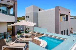 a swimming pool with chairs and an umbrella next to a building at Plakias Galaxy Villas in Plakias