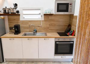 a small kitchen with a sink and a microwave at Le Cocon d'Ava - Bungalows & Spa in Saint-Paul