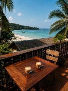 a wooden table on a balcony with a view of the beach at Secret Place Hotel and Restaurant in Haad Yao