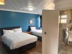 a bedroom with two beds and a blue wall at The Rivenhall Hotel in Rivenhall