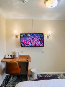 a room with a desk and a television on the wall at The Rivenhall Hotel in Rivenhall