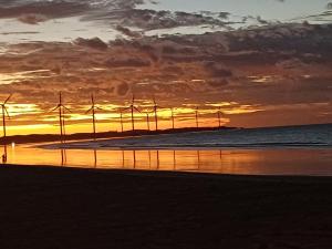 a sunset on the beach with windmills at Villa Moura Pousada in Amontada