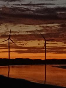 a painting of two windmills in the ocean at sunset at Villa Moura Pousada in Amontada