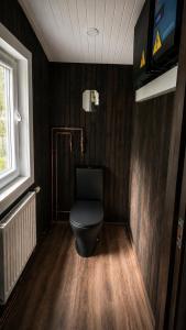 a bathroom with a black toilet in a room at Strazdu Ligzda Off grid treehouse in Meņģele