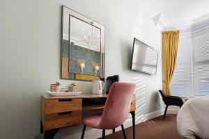 a bedroom with a desk and a pink chair at The Rosedene in Llandudno