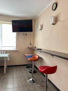 a room with two bar stools and a tv on the wall at SunHouse Hostel in Karakol +7 photos