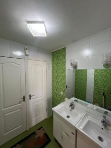 a bathroom with a white sink and a mirror at SunHouse Hostel in Karakol