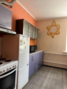a kitchen with a white refrigerator and purple cabinets at SunHouse Hostel in Karakol