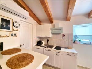 a kitchen with white cabinets and a sink and a clock at Stone House Mate in Rovinjsko Selo