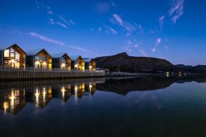 a row of houses by the water at night at Risøyhamn Sjøhus AS in Risøyhamn +35 photos