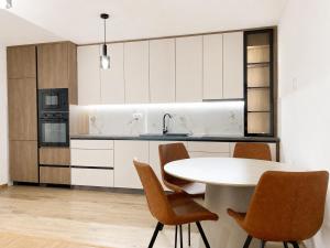 a white kitchen with a table and chairs at Teslić CITY Apartment in Teslić