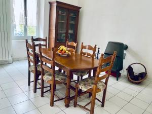 a wooden table and chairs with a bowl of fruit on it at Le cadeau bleu, duplex en Cévennes in La GrandʼCombe