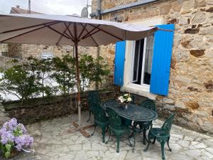 a table and chairs with an umbrella on a patio at Le cadeau bleu, duplex en Cévennes in La GrandʼCombe