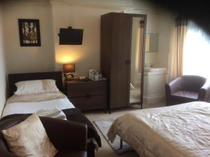 a hotel room with two beds and a chair at Witchingham B&B in Holyhead