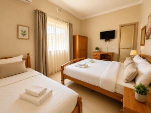 a bedroom with two beds and a television in it at Electra Guesthouse in Marsalforn