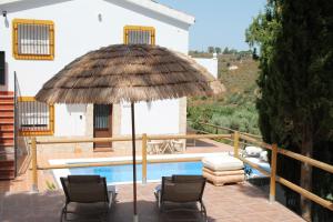 Eine Terrasse mit Stühlen und einem Sonnenschirm neben einem Pool in der Unterkunft Marimonta in Cómpeta