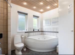 a white bathroom with a tub and a toilet at Feriehus 1104 in Ringkøbing +26 photos