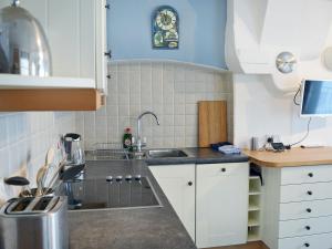 a small kitchen with white cabinets and a sink at Ferrydown in Salcombe