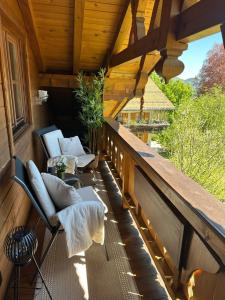 a porch with chairs and a table on a wooden deck at Ferienwohnung Haus Reindl in Walchensee