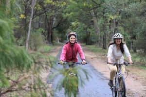 two women riding bikes down a dirt road at Chalets Lumineux in Bright