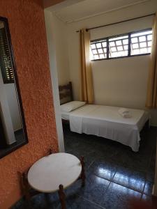 a room with two beds and a table and a window at Pousada Coqueiro Verde in Mateus Leme +15 photos