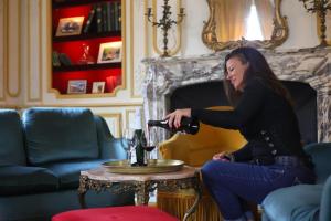 a woman pouring a glass of wine in a living room at Chambres d hôtes dans maison bourgeoise Douce France in Millau