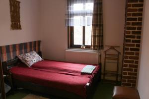 a small bedroom with a red bed with a window at Casa Kővár Vendégház in Rimetea