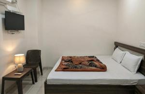 a bedroom with a bed and a chair and a television at Hotel Aarav Grand Chandigarh in Chandīgarh