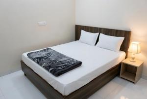 a bed with a black and white blanket on it at Hotel Aarav Grand Chandigarh in Chandīgarh