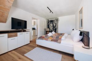 a white bedroom with a bed and a flat screen tv at KUL App 5 by Alpenidyll Apartments in Öblarn