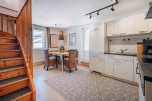 a kitchen with white cabinets and a table with chairs at KUL App 5 by Alpenidyll Apartments in Öblarn