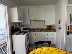 a small kitchen with white cabinets and a table at Le Petit Saint-Joseph in Saint-Alexis-des-Monts +6 photos