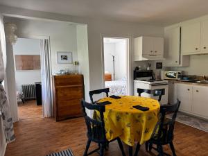 a kitchen with a table with a yellow table cloth on it at Le Petit Saint-Joseph in Saint-Alexis-des-Monts