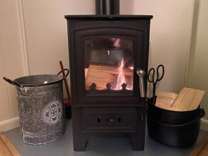 a wood stove sitting next to a trash can at Corran Shepherds Hut in Corran