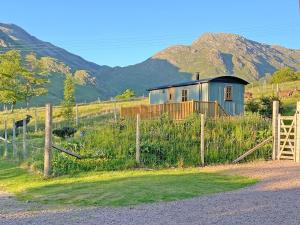 a house in a field with mountains in the background at Corran Shepherds Hut in Corran