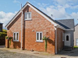a red brick house with white windows and flowers at Bwthyn Bwlch in Denbigh