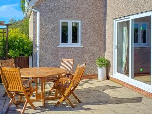 a wooden table and chairs on a patio at Bwthyn Bwlch in Denbigh +3 photos
