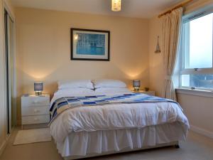 a bedroom with a bed with white sheets and a window at Brae Lodge in Cullen +5 photos